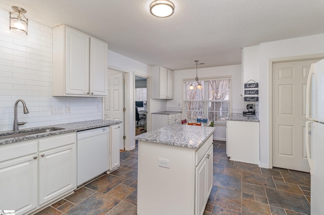 kitchen featuring pendant lighting, white appliances, a center island, and white cabinets