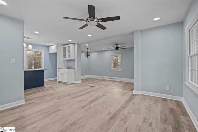 unfurnished living room with ceiling fan, sink, and light hardwood / wood-style floors