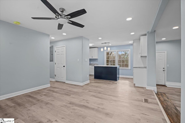 unfurnished living room with ceiling fan, electric panel, and light hardwood / wood-style floors