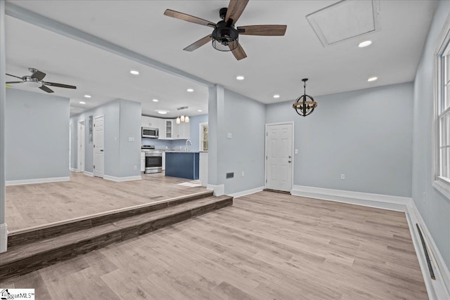 unfurnished living room featuring ceiling fan, sink, and light wood-type flooring