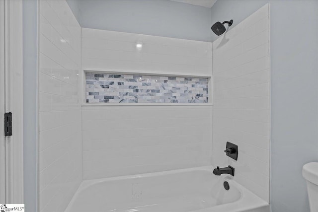 bathroom with toilet and tiled shower / bath combo