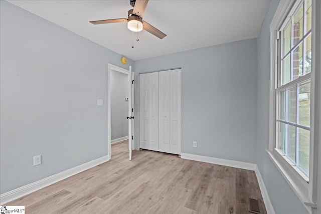 unfurnished bedroom featuring ceiling fan, a closet, and light wood-type flooring