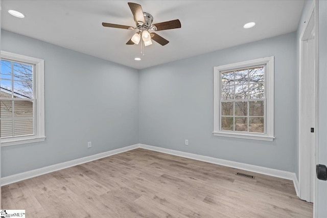 spare room featuring a healthy amount of sunlight, ceiling fan, and light hardwood / wood-style flooring