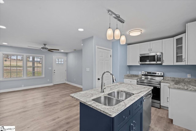 kitchen featuring sink, stainless steel appliances, blue cabinets, white cabinets, and a center island with sink