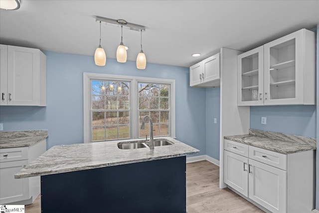 kitchen featuring white cabinetry, sink, decorative light fixtures, and a kitchen island with sink