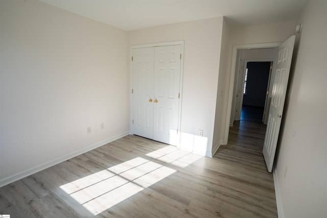 unfurnished bedroom with a closet and light wood-type flooring