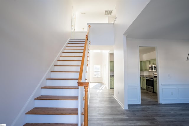 staircase with hardwood / wood-style flooring and ornamental molding