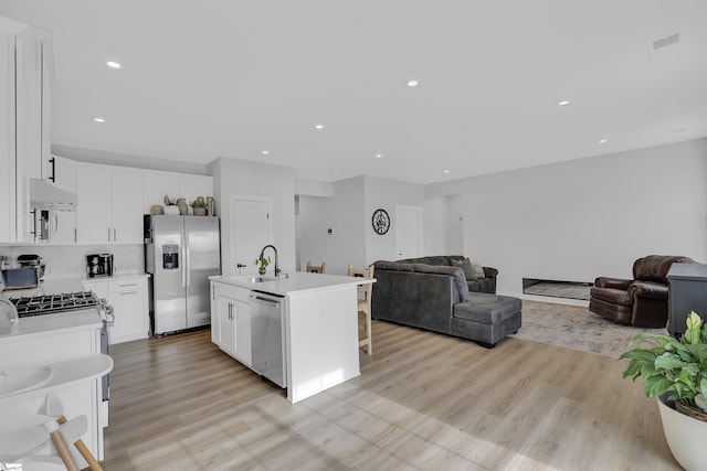 kitchen featuring sink, a kitchen island with sink, stainless steel appliances, light hardwood / wood-style floors, and white cabinets