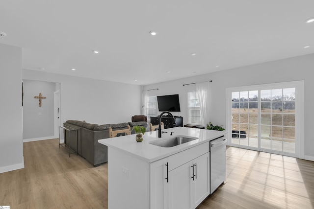 kitchen featuring sink, white cabinetry, light wood-type flooring, stainless steel dishwasher, and a kitchen island with sink