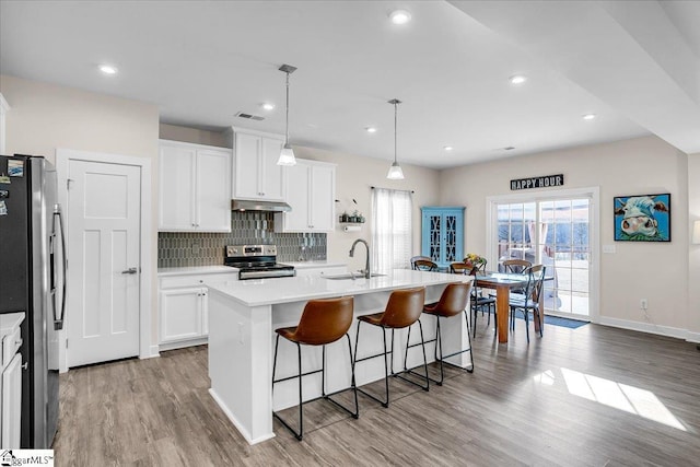 kitchen with sink, stainless steel appliances, hanging light fixtures, and a center island with sink