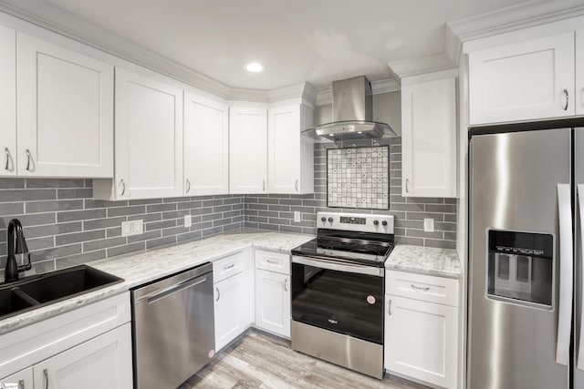 kitchen with wall chimney range hood, light stone countertops, white cabinets, and appliances with stainless steel finishes