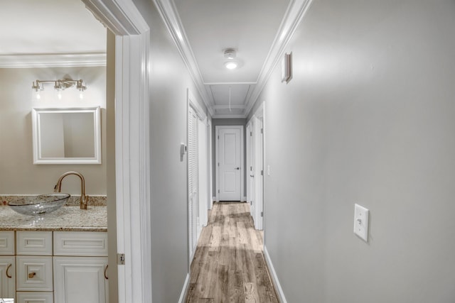 corridor featuring ornamental molding, sink, and light hardwood / wood-style flooring