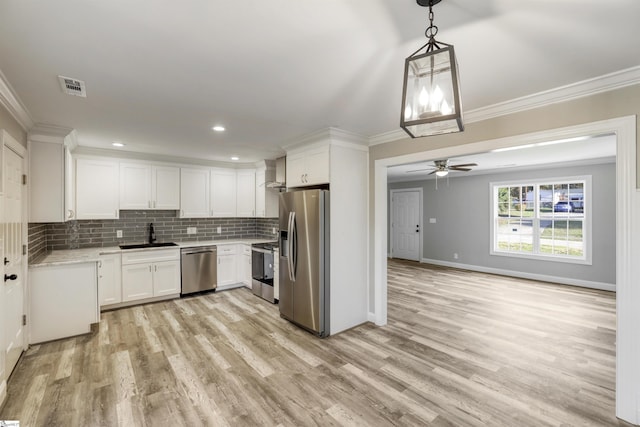 kitchen featuring white cabinetry, appliances with stainless steel finishes, decorative light fixtures, and crown molding