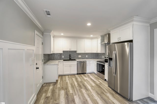 kitchen with tasteful backsplash, white cabinetry, sink, stainless steel appliances, and wall chimney range hood