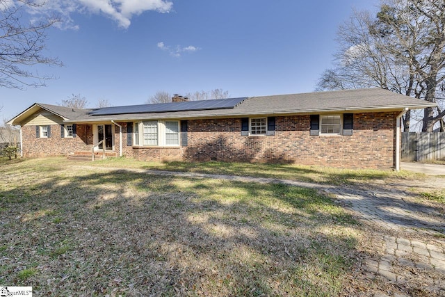 ranch-style home with a front lawn and solar panels