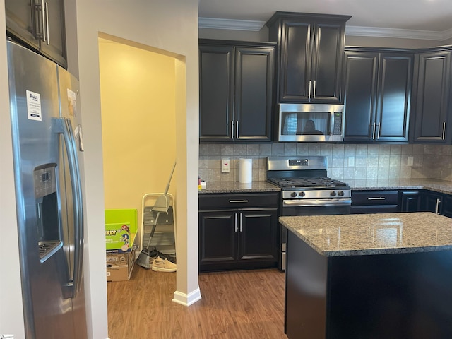 kitchen featuring tasteful backsplash, ornamental molding, appliances with stainless steel finishes, and light hardwood / wood-style flooring
