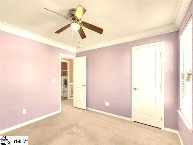 unfurnished bedroom featuring crown molding, ceiling fan, washer / dryer, and light carpet
