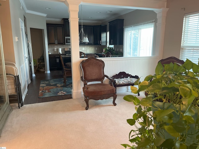 living area with ornamental molding and ornate columns