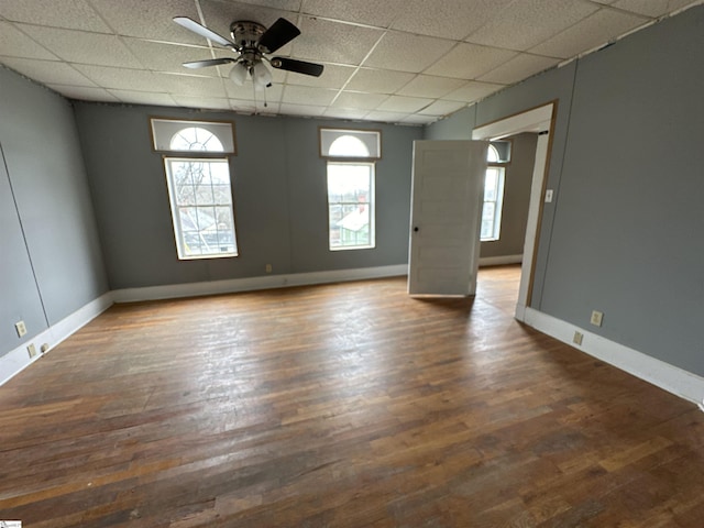 empty room with ceiling fan, a paneled ceiling, and dark hardwood / wood-style flooring