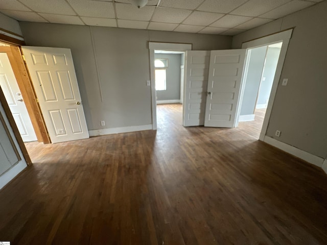 spare room with a paneled ceiling and dark hardwood / wood-style floors