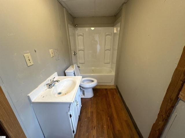 full bathroom with a paneled ceiling, hardwood / wood-style floors, shower / bath combination, vanity, and toilet