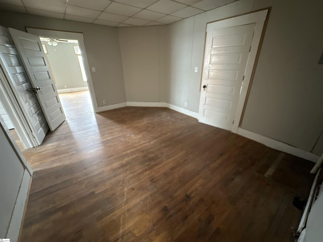 empty room featuring a drop ceiling, wood-type flooring, and ceiling fan