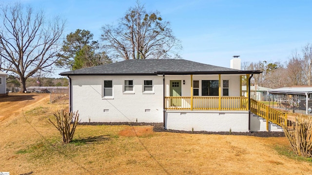 rear view of house with covered porch and a lawn