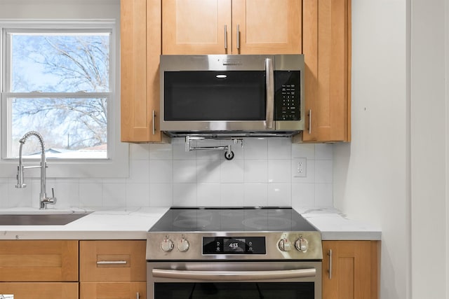 kitchen featuring light stone counters, sink, decorative backsplash, and stainless steel appliances