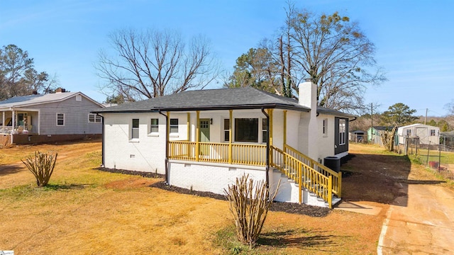 view of front of house featuring cooling unit, a front yard, and covered porch