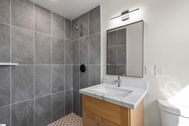 bathroom featuring vanity, toilet, and a tile shower