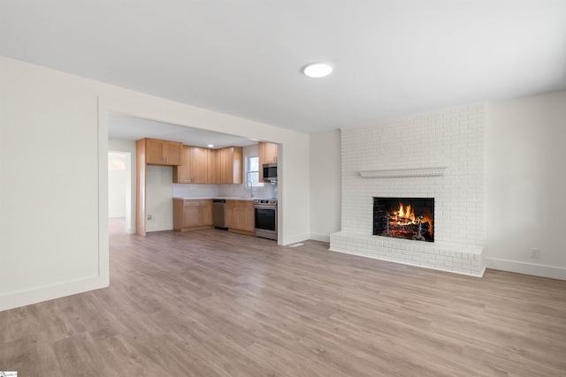 unfurnished living room featuring sink, a fireplace, and light hardwood / wood-style floors