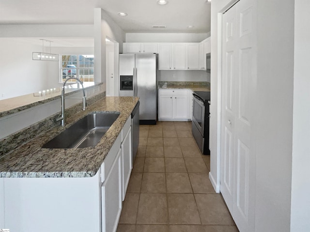 kitchen with dark stone countertops, stainless steel appliances, sink, and white cabinets