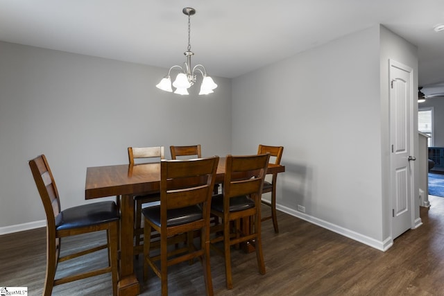 dining room with dark wood-type flooring and an inviting chandelier