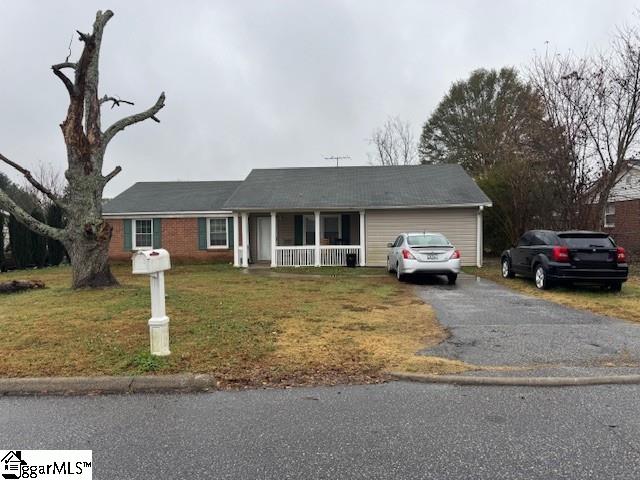 single story home with a garage, a front lawn, and covered porch