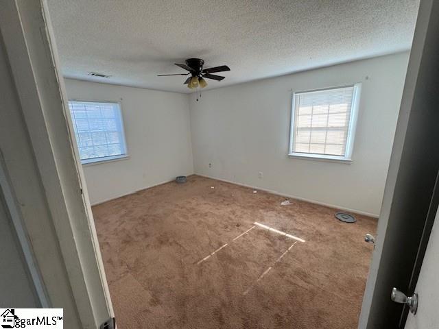 carpeted empty room with ceiling fan and a textured ceiling