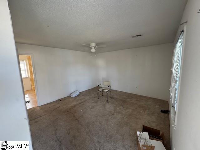 carpeted empty room featuring ceiling fan and a textured ceiling