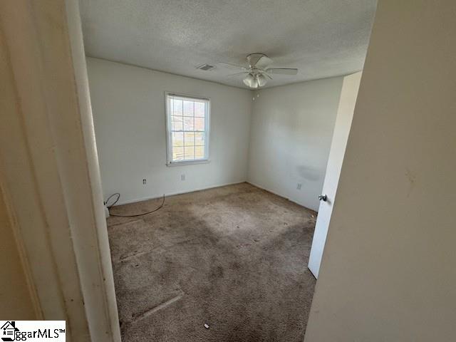 carpeted empty room featuring ceiling fan and a textured ceiling