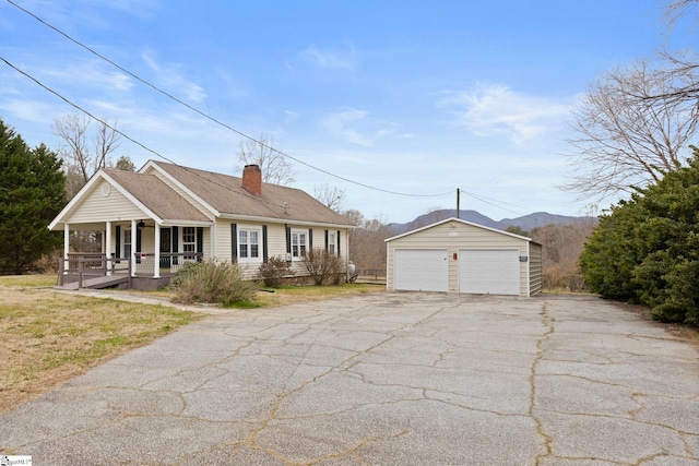 ranch-style house with a porch, a garage, an outdoor structure, a mountain view, and a front lawn