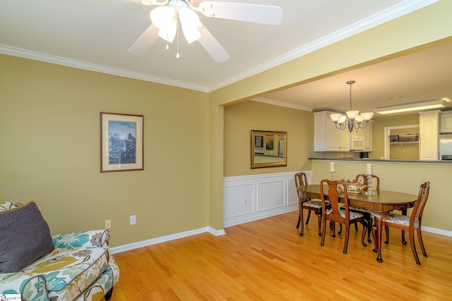 dining space with ceiling fan with notable chandelier, ornamental molding, and light hardwood / wood-style floors