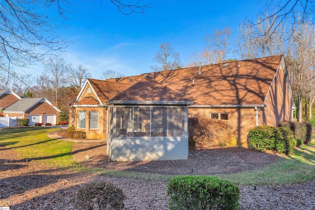rear view of house featuring a yard and a sunroom