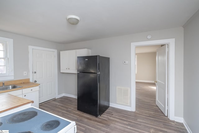 kitchen featuring black refrigerator, white electric range, dark wood-type flooring, and white cabinets