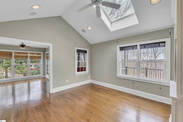 spare room with ceiling fan, hardwood / wood-style flooring, and vaulted ceiling with skylight