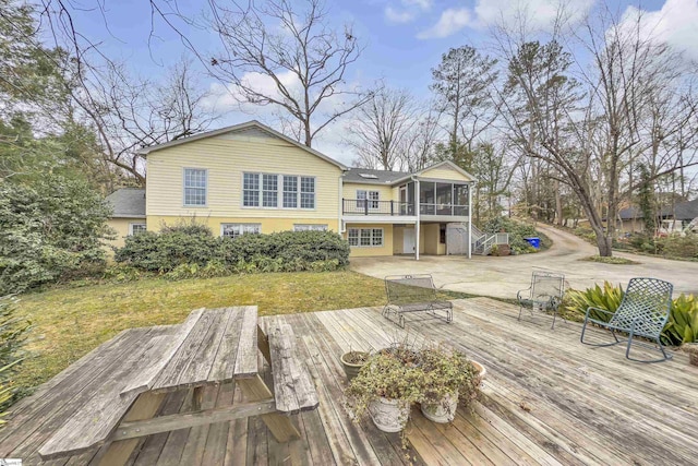 rear view of house with a sunroom, a yard, a deck, and a patio area