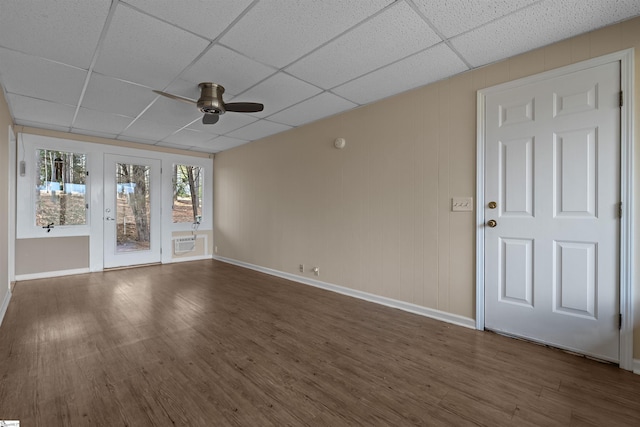 unfurnished room featuring dark wood-type flooring, ceiling fan, a paneled ceiling, and a wall unit AC