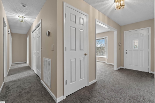 carpeted foyer with a textured ceiling