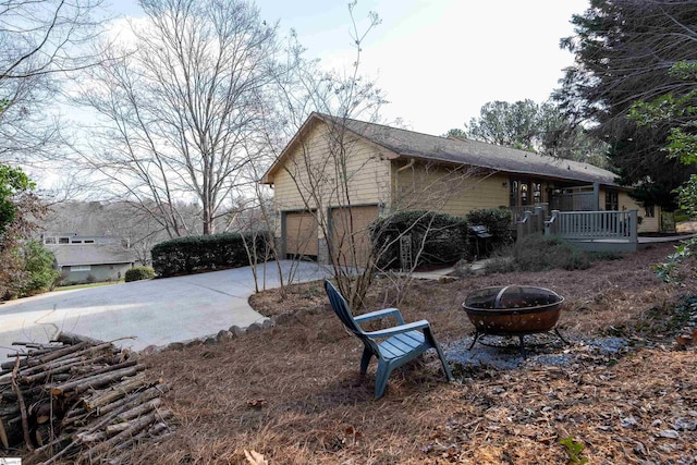 view of home's exterior featuring a garage, a deck, and an outdoor fire pit