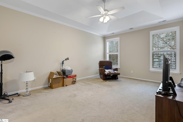 interior space with light carpet, a tray ceiling, crown molding, and ceiling fan