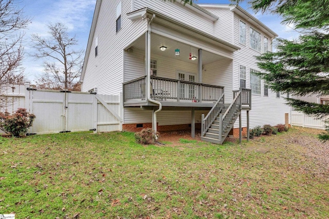 rear view of property featuring a wooden deck and a lawn