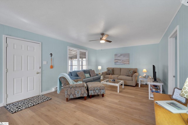 living room with ceiling fan, a baseboard heating unit, and light wood-type flooring