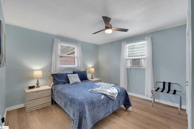 bedroom with cooling unit, a textured ceiling, ceiling fan, and light hardwood / wood-style flooring